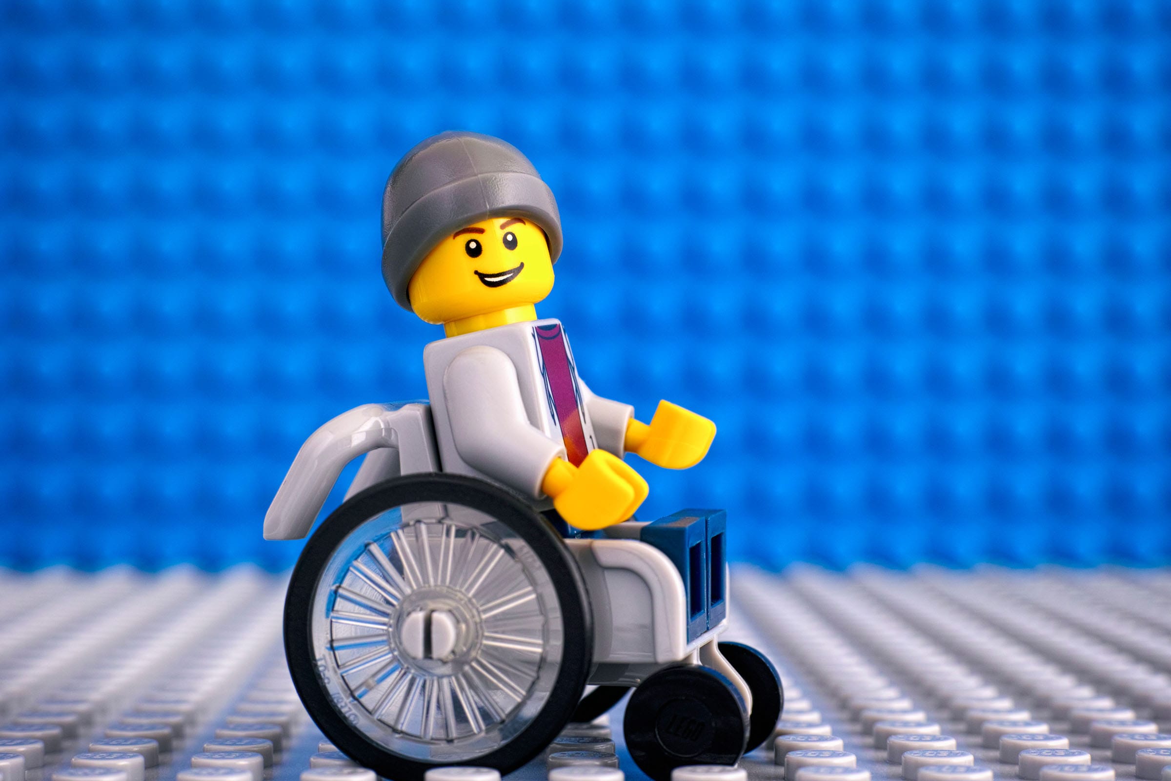 Lego figure in wheelchair on blue background.